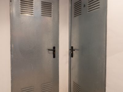 Two grey metallic doors with upper and lower vents, one marked 'Benissa Denia' and the other with the number '5', set on a speckled granite floor.