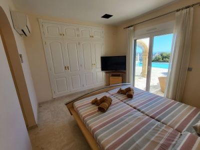 Bedroom featuring twin beds, a built-in wardrobe, and direct access to the pool area. Includes a TV, air conditioning, and tiled flooring.