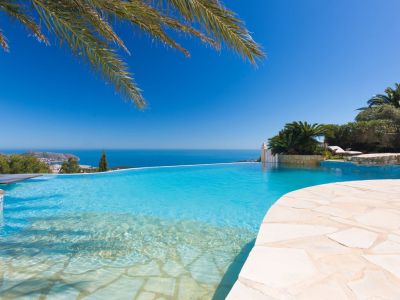 Infinity pool featuring a beach-style entry and light stone coping, providing panoramic views of the Mediterranean Sea and distant coastline.