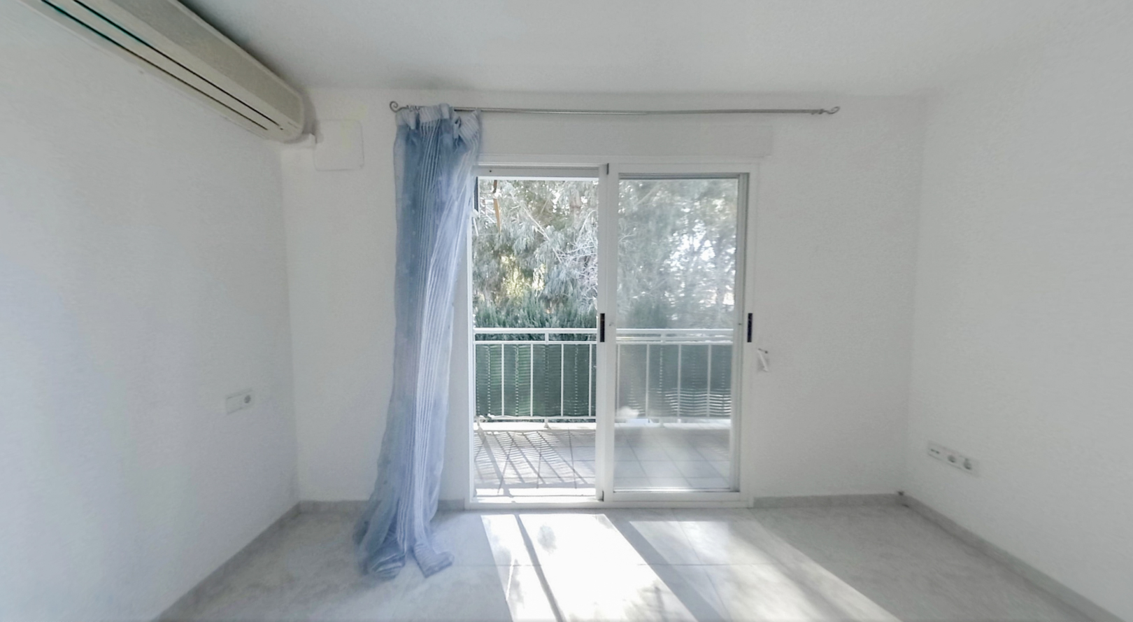 Bright bedroom featuring an air conditioning unit and direct access to a private terrace. Light tiled flooring and views of lush greenery.