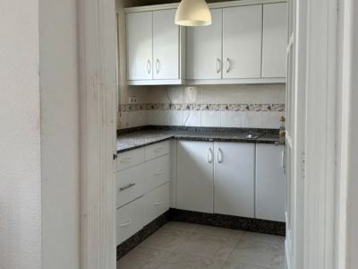 Functional kitchen featuring white cabinetry, dark speckled granite countertops, and a tiled backsplash. A single pendant light illuminates the space, ready for personalization.