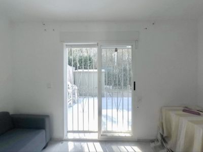 Spacious room with sliding glass doors and security bars, providing direct access to the private garden, illuminated by abundant natural light on the light-toned floor.