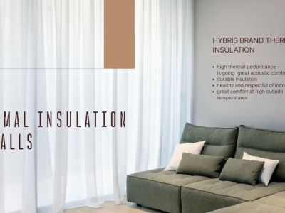 Interior detail illustrating advanced wall thermal insulation, featuring a contemporary corner sofa and elegant sheer curtains.