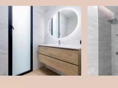 Modern bathroom featuring a floating wooden vanity, an illuminated oval mirror, and a rain shower. Marble-look and textured wall tiles.