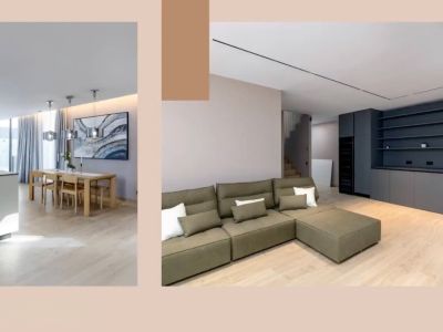 Open-plan living area featuring a modern kitchen island, wooden dining set, and an olive-green sectional sofa. Dark grey built-in storage and sleek lighting complete the contemporary design.