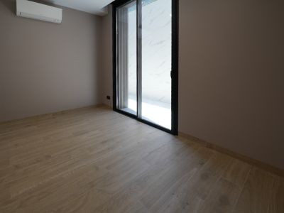 Unfurnished room with light wood-look tile flooring, taupe walls, and a black-framed sliding glass door. A wall-mounted AC unit is visible.