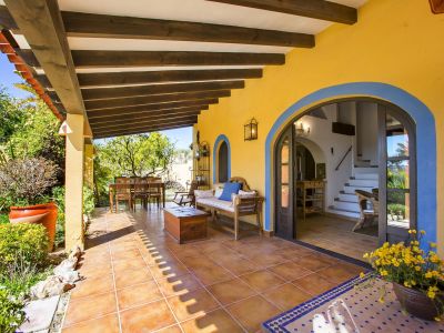 Covered porch with wood beams, terracotta tile floor, and interior access through a blue archway.