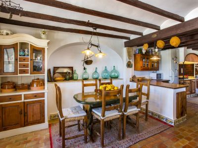 Rustic dining area with oval table, wooden chairs, and traditional-style cupboard. Exposed wooden beams on the ceiling.