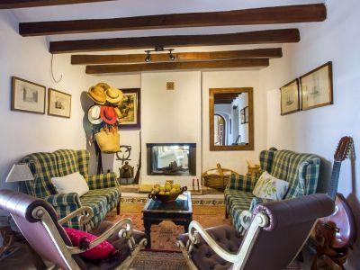 Rustic living room featuring a fireplace, plaid armchairs, and exposed wood beams. Traditional decor and natural light.