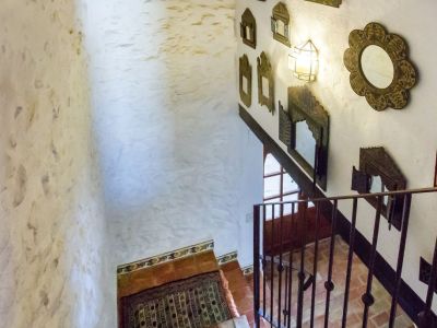 Stairway detail with terracotta steps and a wall decorated with rustic mirrors in Teulada.