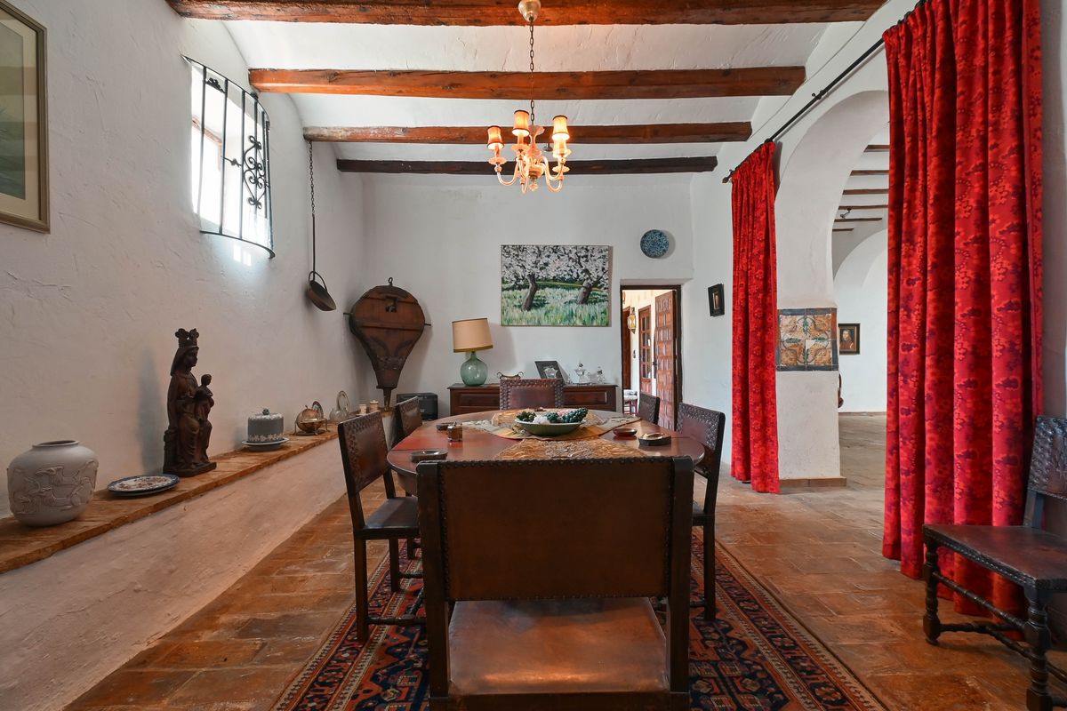 Rustic dining room featuring exposed wooden ceiling beams, terracotta tile flooring, and traditional leather chairs under a classic chandelier.