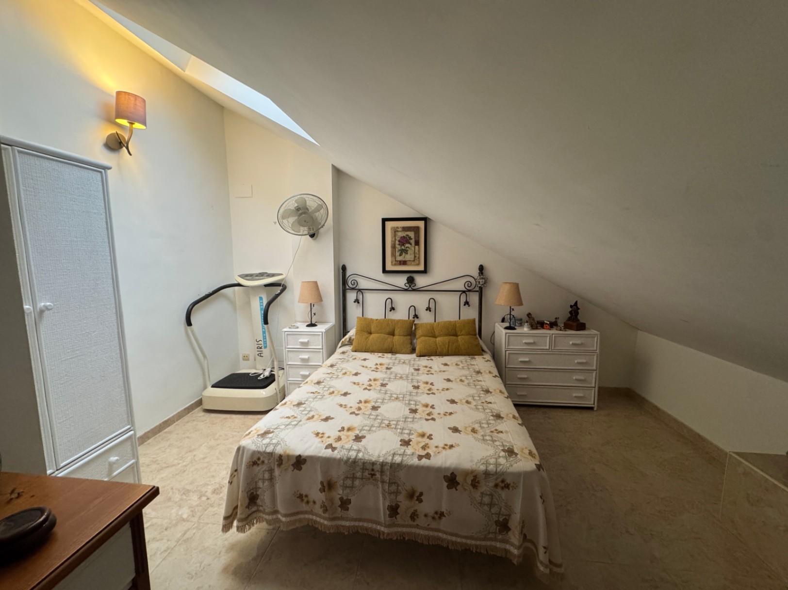 Attic bedroom featuring a double bed, exercise machine, and white wardrobes.