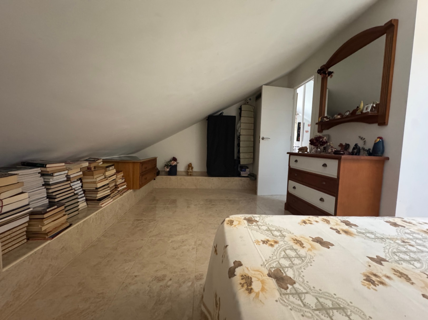 Attic bedroom with integrated bookshelf and wooden dresser.