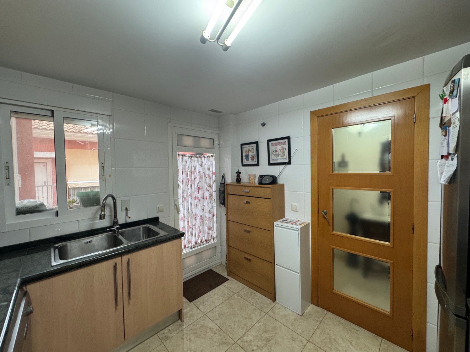 Functional kitchen featuring a black granite countertop, ceramic tile flooring, and a wood door with glass panels.