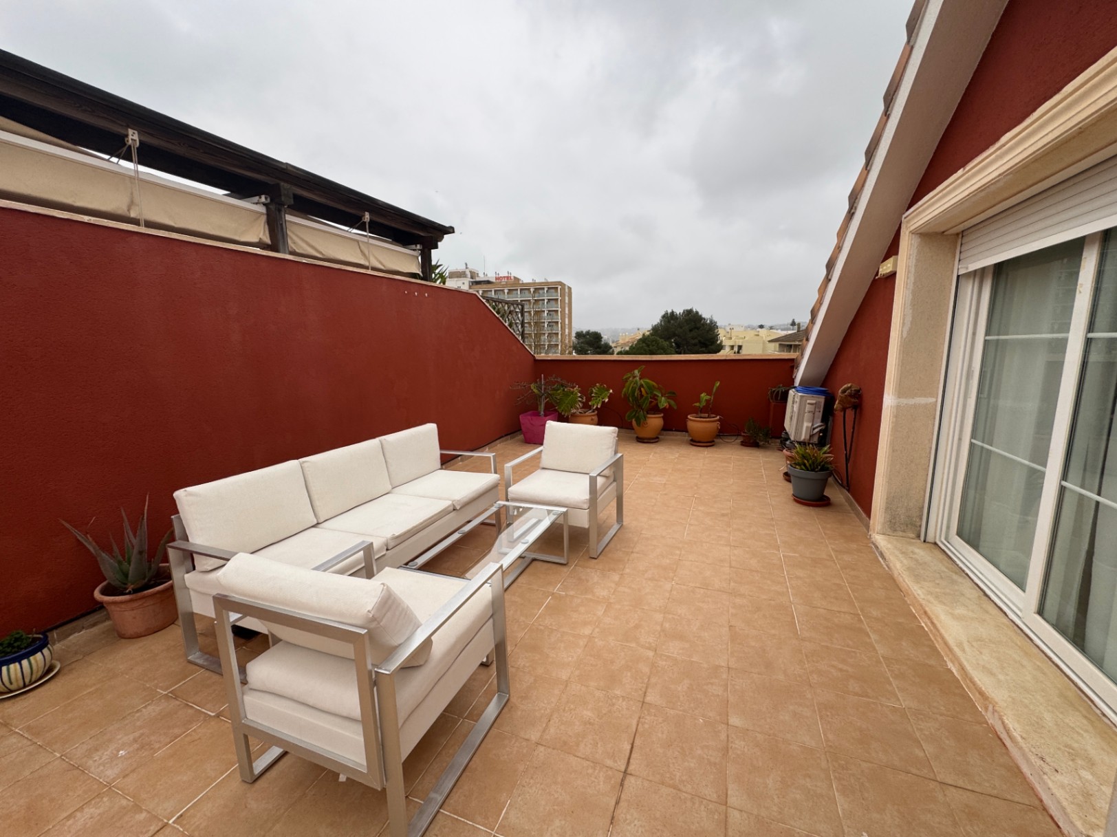 Terrace with ceramic tile flooring, red walls, and aluminum outdoor furniture.