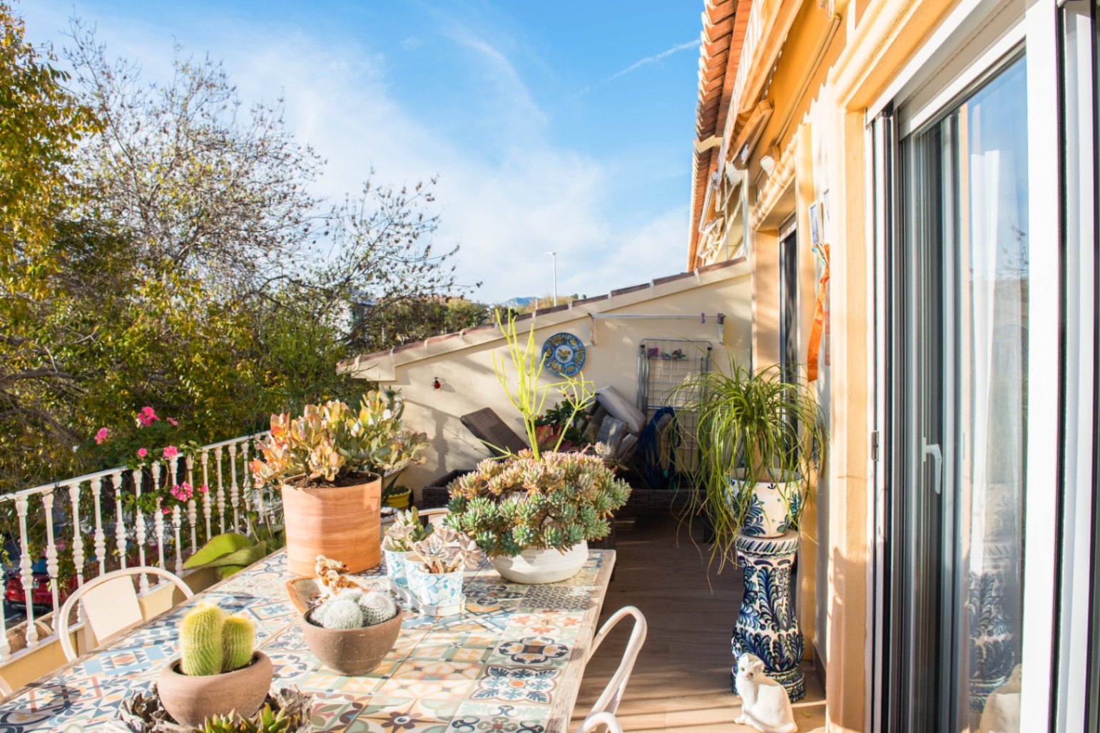 Outdoor terrace featuring a decorative tiled table, a variety of potted succulents, and direct access through sliding glass doors.