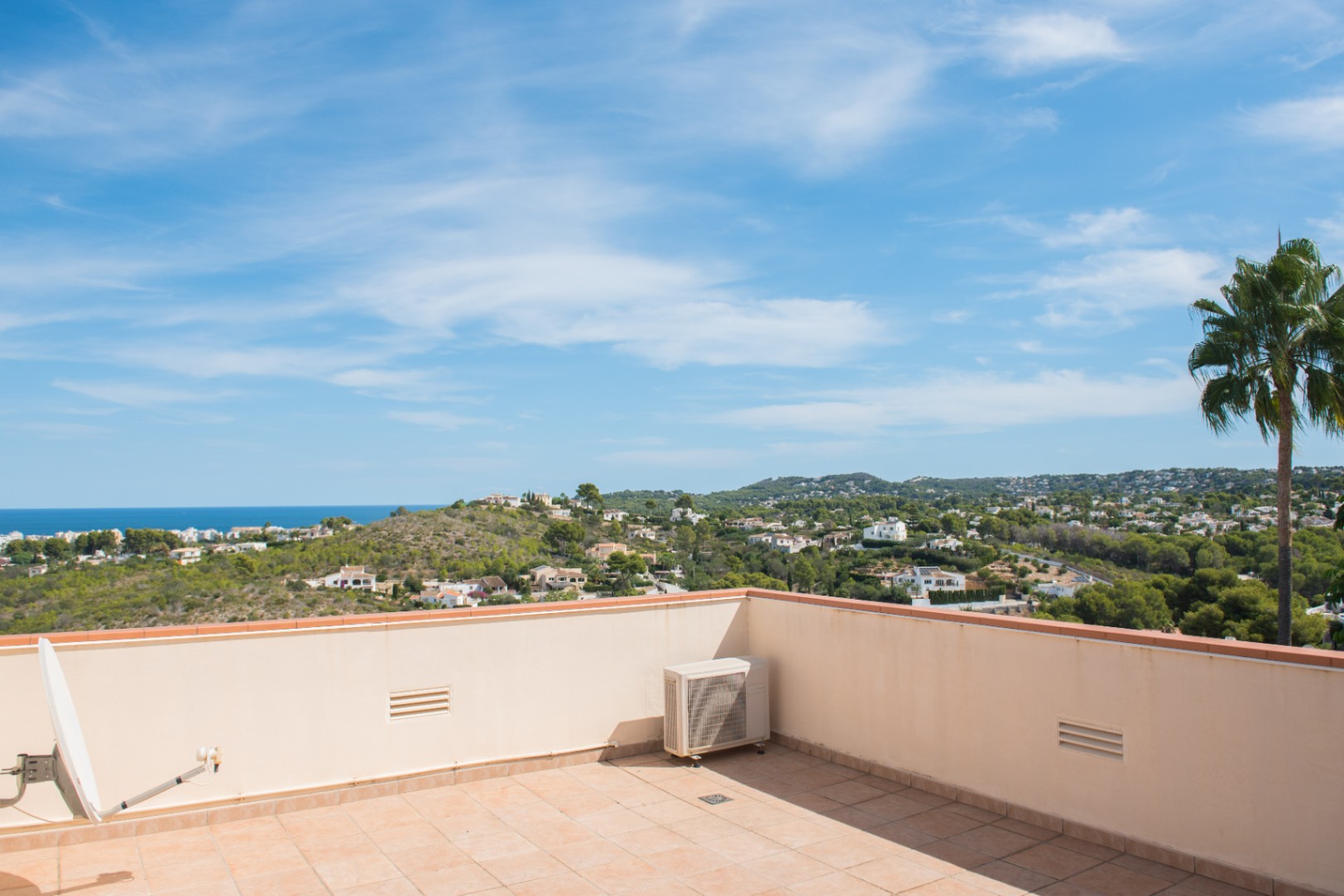 Rooftop terrace with terracotta tiles offering panoramic views of the Mediterranean coastline, surrounding hills, and residential areas.