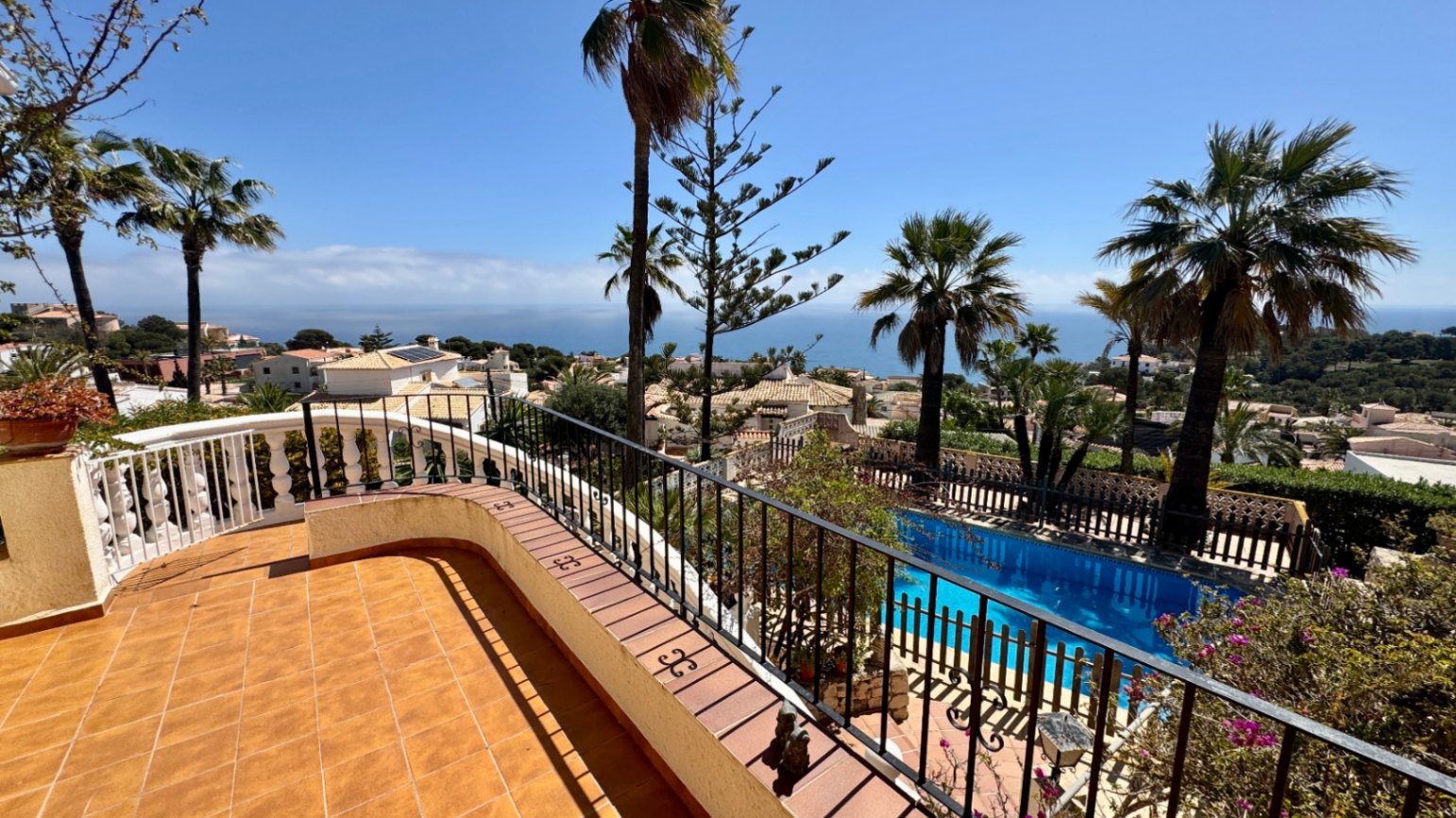 Elevated terrace with terracotta tiling and wrought iron railings overlooking a private swimming pool and the Mediterranean Sea.