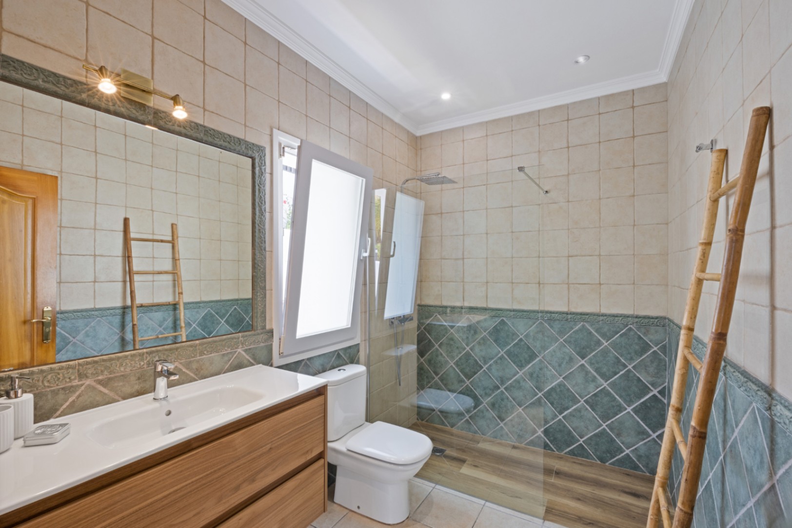 Bathroom featuring a walk-in shower with wood-effect flooring, green diamond-patterned wall tiles, a wooden vanity, and a decorative bamboo ladder towel rack.