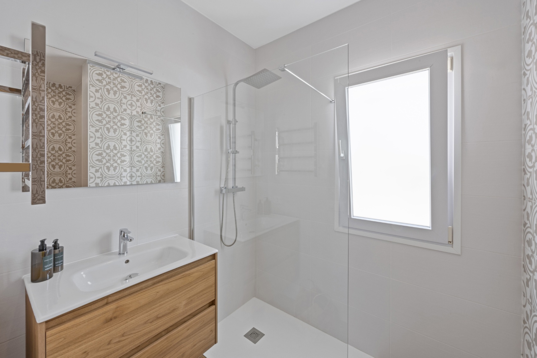 Modern bathroom with a wood-grain vanity, integrated ceramic sink, and a walk-in shower featuring a glass screen and chrome rain showerhead.