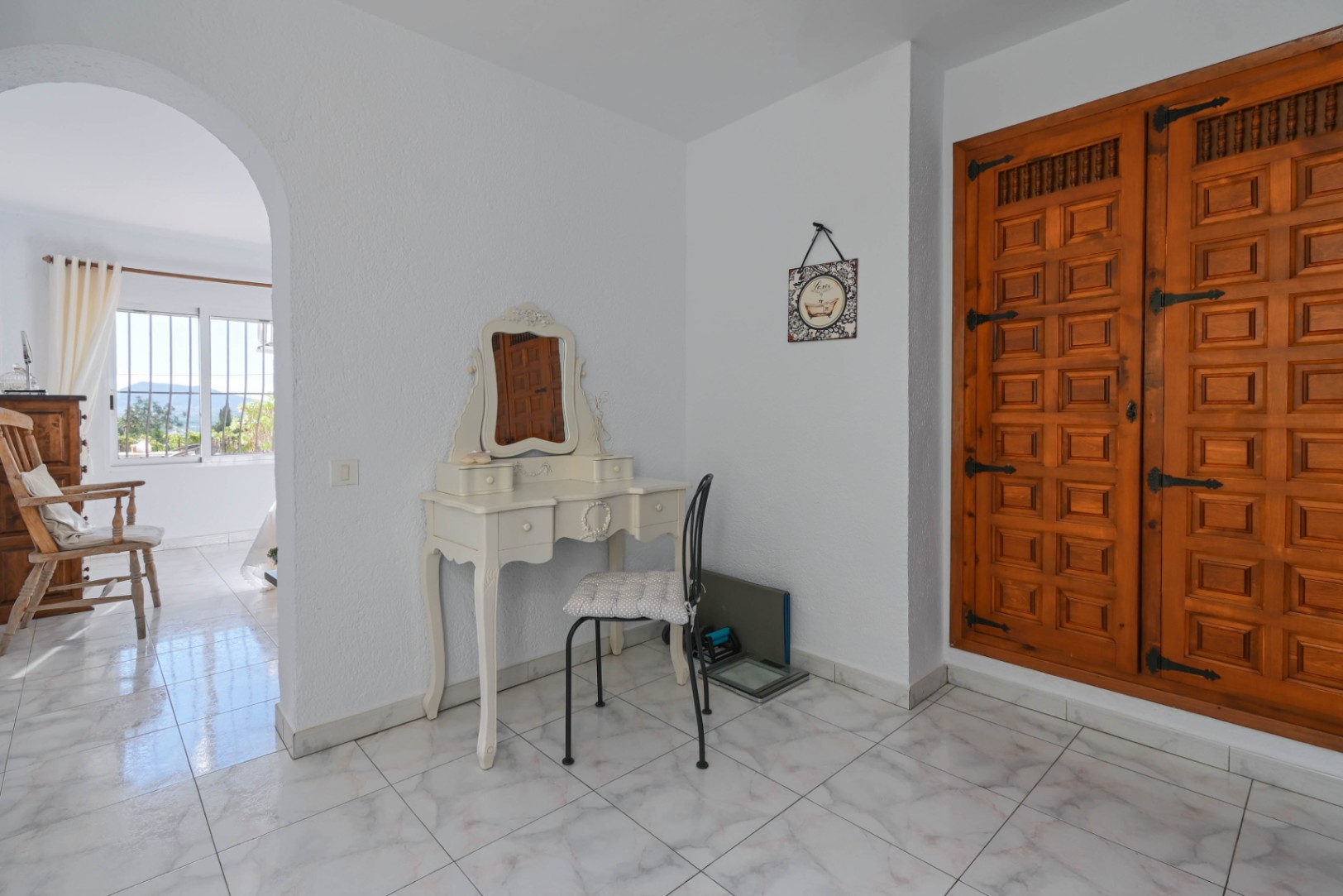 Dressing area featuring a vintage-style white vanity table and a large built-in wooden wardrobe with traditional carved panels and iron hardware.
