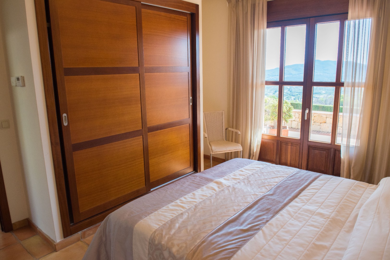 Bedroom featuring a built-in wooden wardrobe with sliding doors, natural light, and access to a terrace with mountain views.