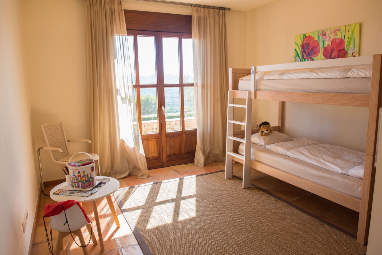 Children's bedroom featuring a wooden bunk bed, terracotta tile flooring, and a large glass door opening to a terrace with mountain views.