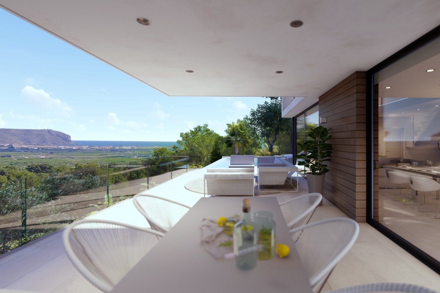 Covered terrace featuring a dining area with woven chairs, lounge seating, and glass railings overlooking the valley and sea.