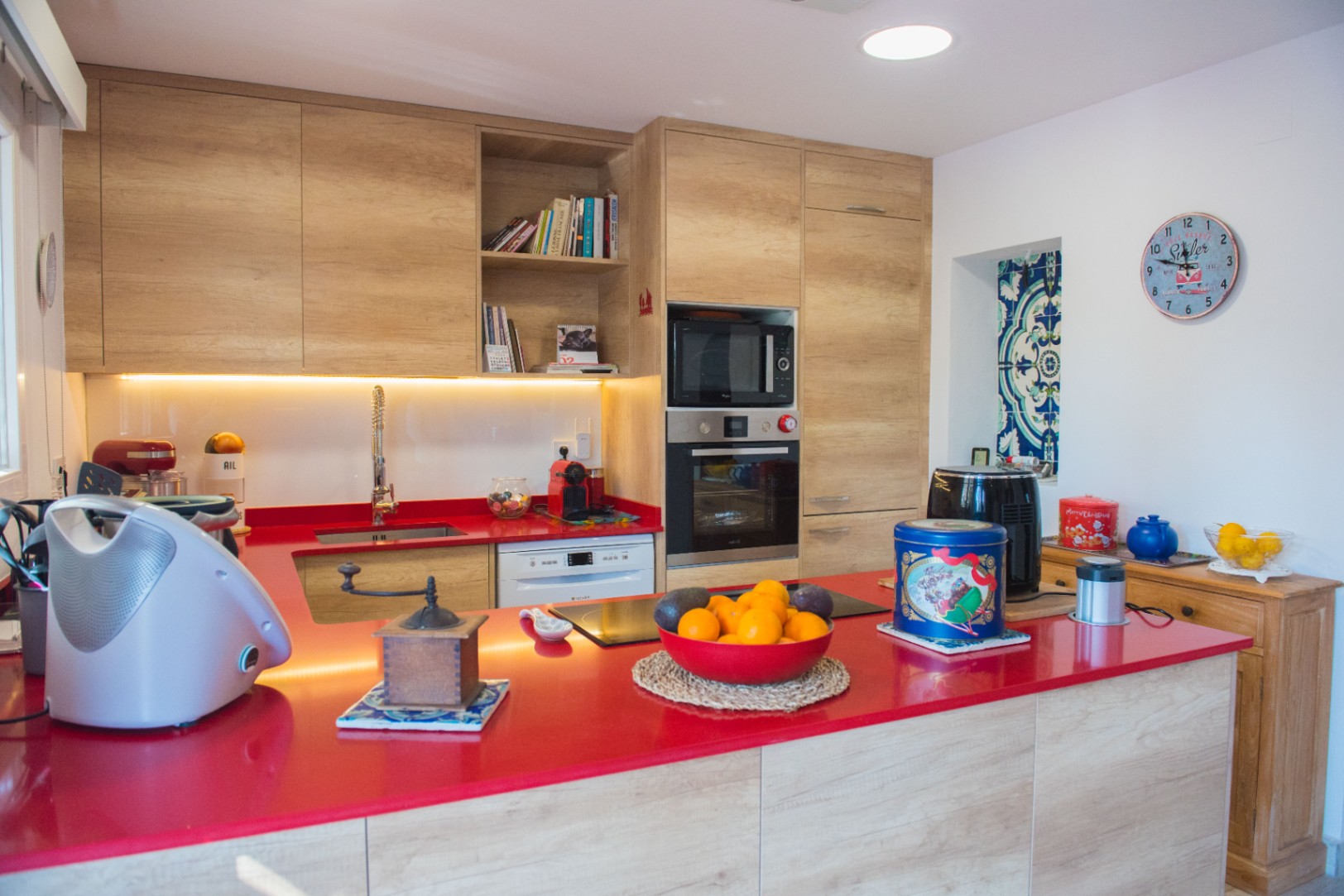 Modern kitchen featuring a vibrant red countertop, light wood cabinetry, and integrated appliances including a built-in oven and induction cooktop.