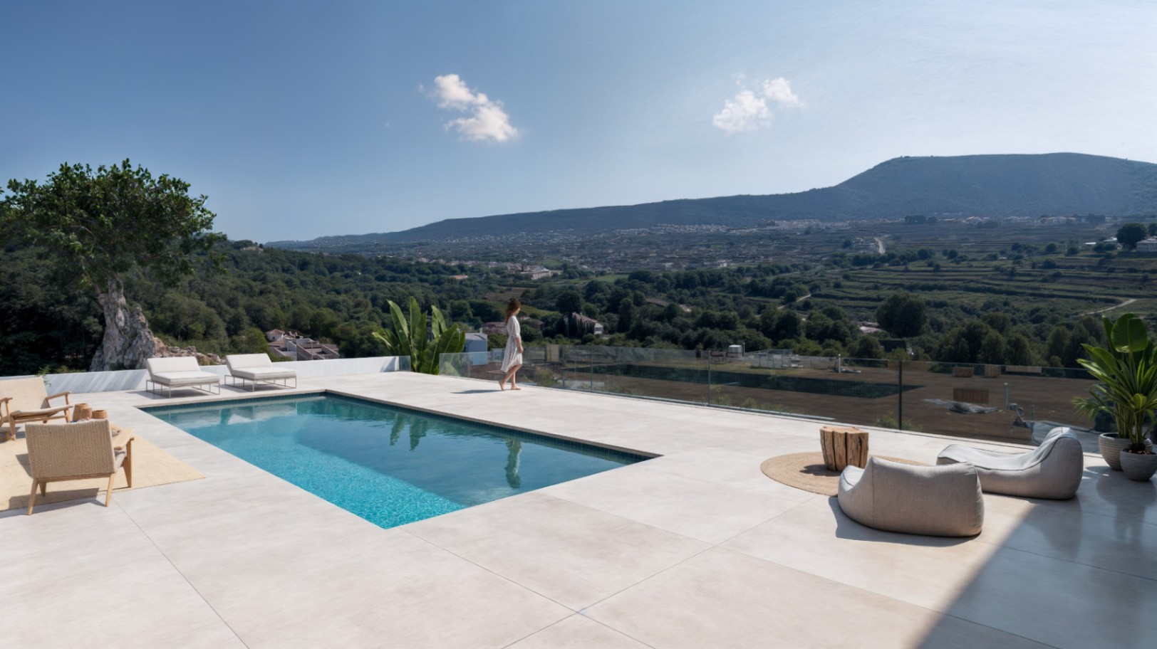 Elevated terrace featuring a rectangular swimming pool, large-format stone tiling, and glass railings overlooking a verdant valley and mountain landscape.