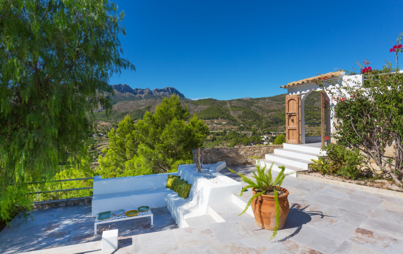Terrace featuring white masonry seating, stone paving, and panoramic views of the mountain landscape and valley.