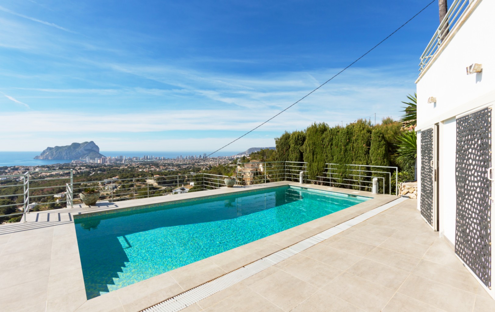 Rectangular outdoor pool with a tiled terrace and metal railing, offering panoramic views of the Mediterranean Sea and the Peñón de Ifach in Calpe.