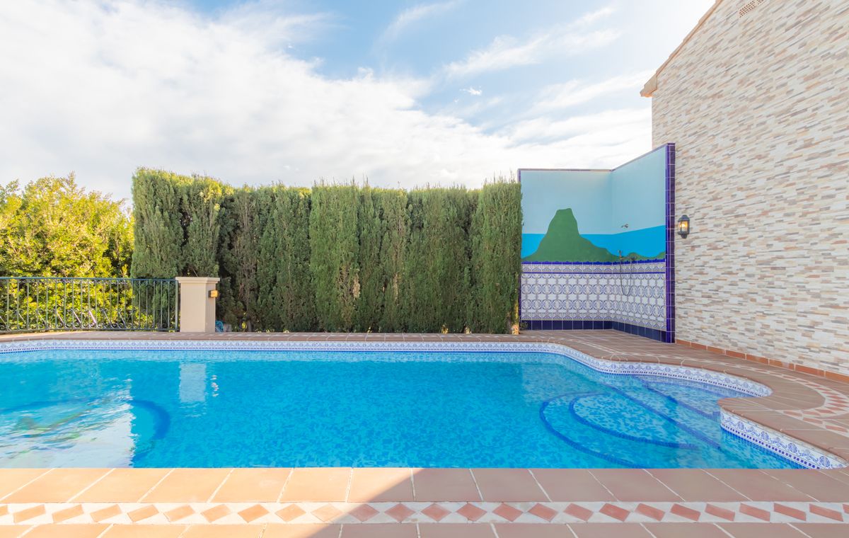 Outdoor swimming pool with curved entry steps, terracotta tiling, and a private shower area featuring a landscape mural and traditional patterned tiles.