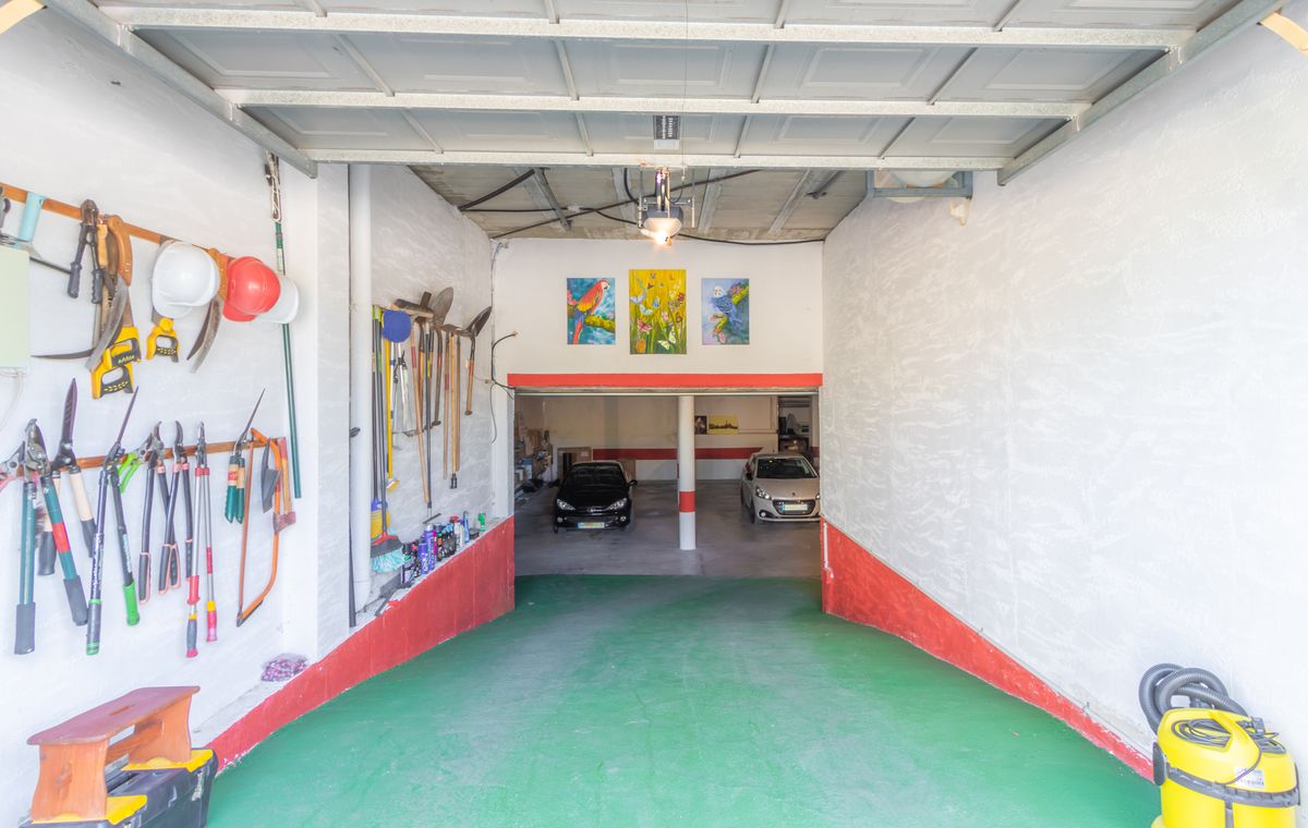 Spacious garage featuring a green access ramp, organized tool storage on white walls, and a lower level with parking for multiple vehicles.