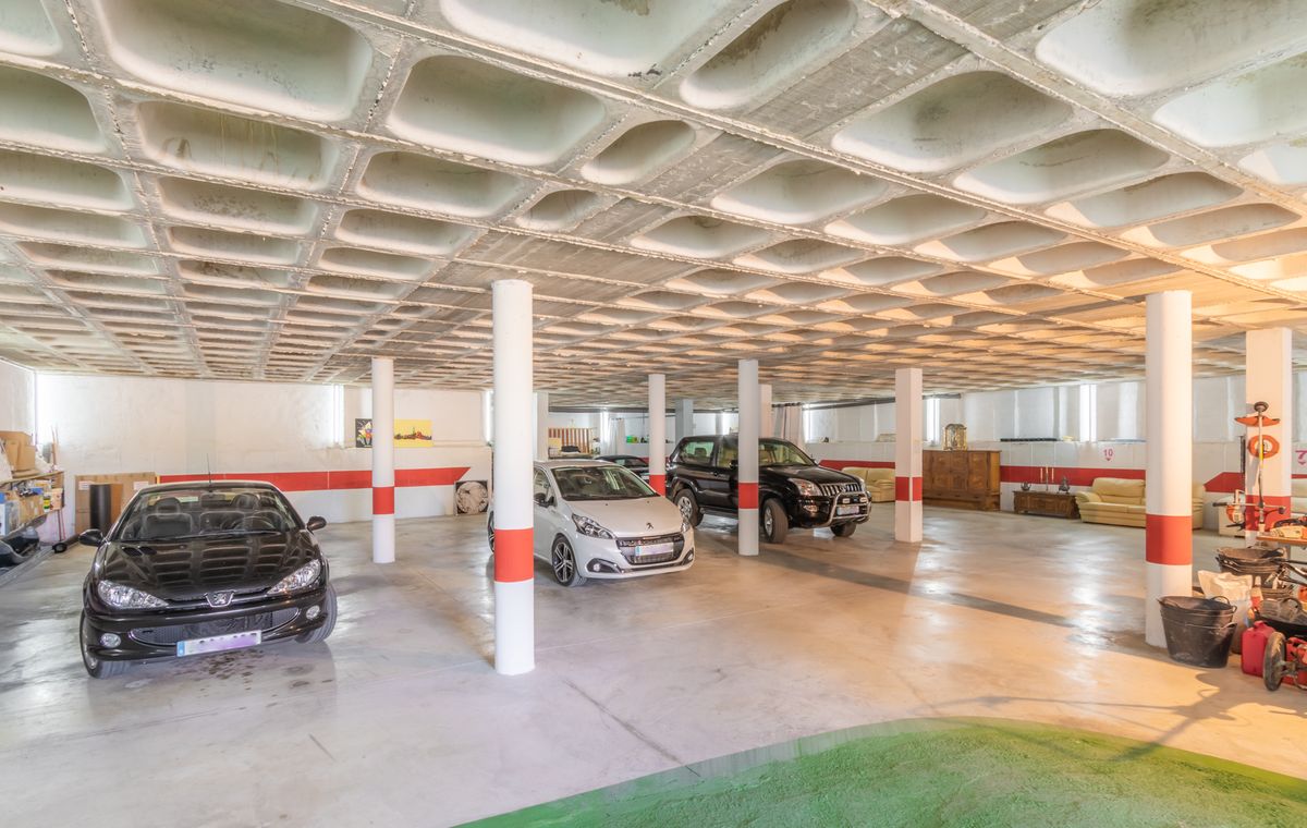 Spacious underground garage featuring a distinctive waffle slab concrete ceiling, white support columns with red safety markings, and ample space for multiple vehicles.