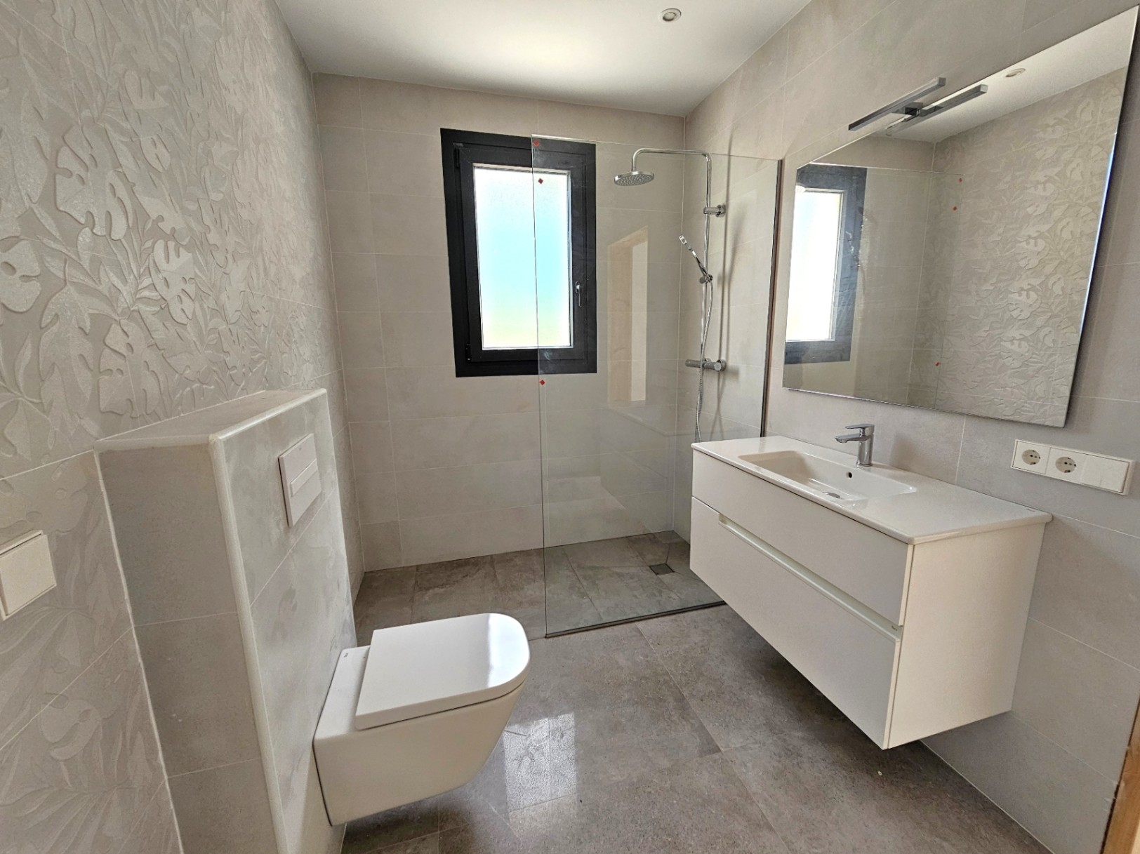 Modern bathroom featuring a walk-in shower, white floating vanity, and a floral textured accent wall.