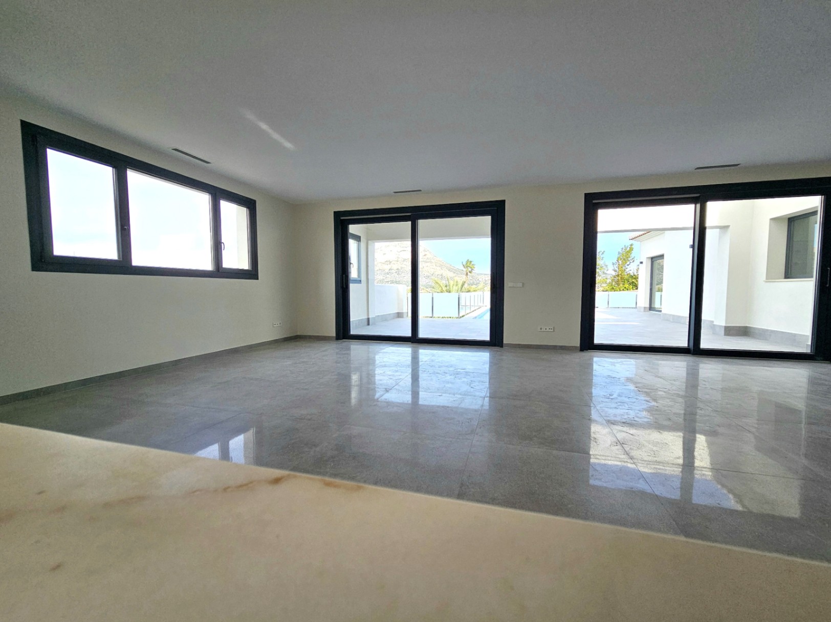 Spacious living room featuring porcelain tile flooring and access to the outdoor terrace through large sliding glass doors.