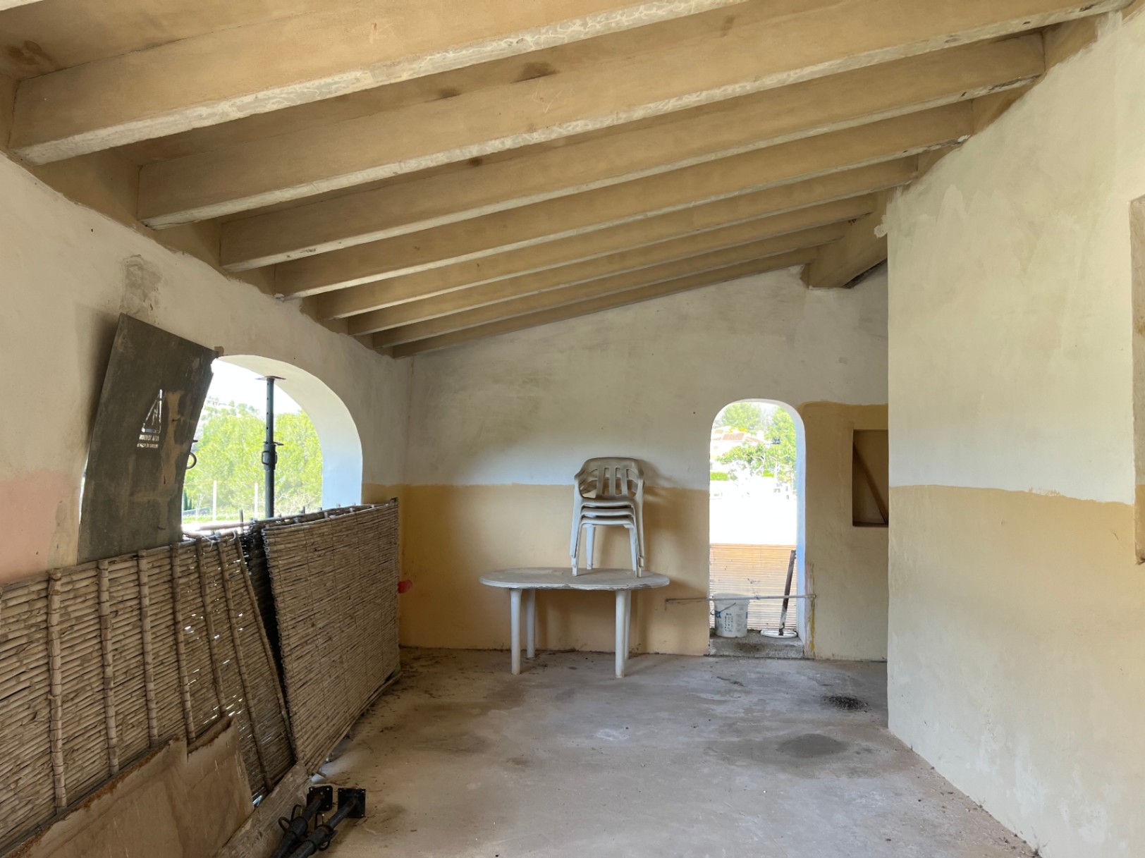 Interior space featuring a sloped ceiling with exposed wooden beams and traditional arched openings. The room is in its original state, ready for complete renovation.