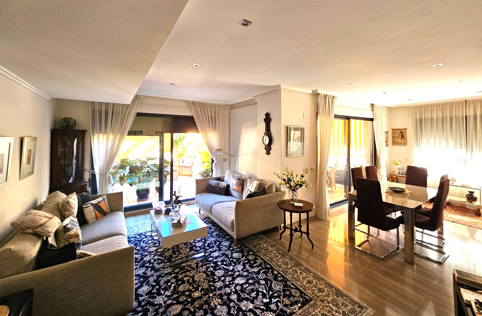 Open-plan living and dining area featuring polished stone floors, recessed ceiling lights, and large sliding glass doors leading to a private terrace.