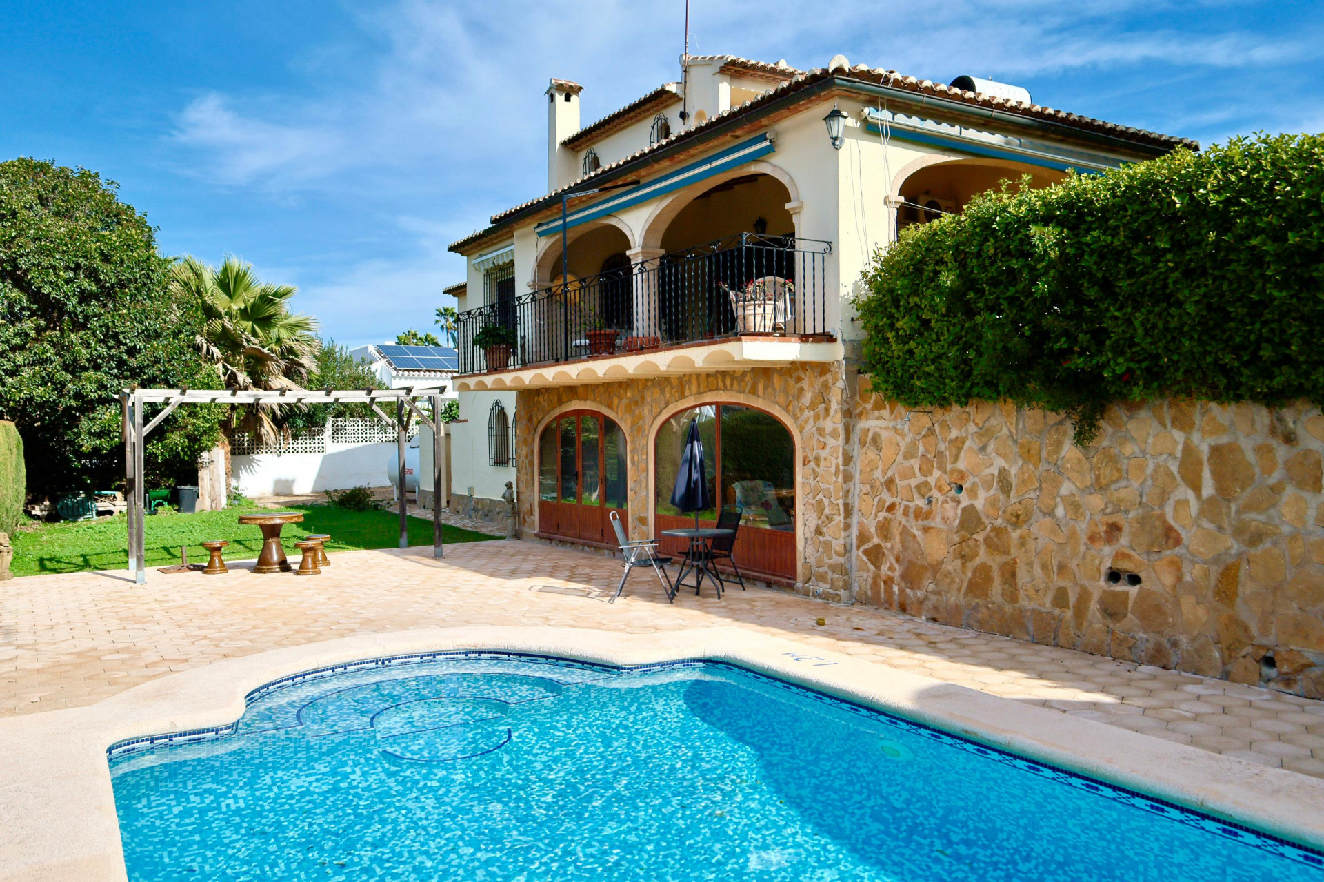 Exterior featuring a private pool, natural stone facade, arched windows, and a large upper terrace with traditional arches and wrought iron railings.