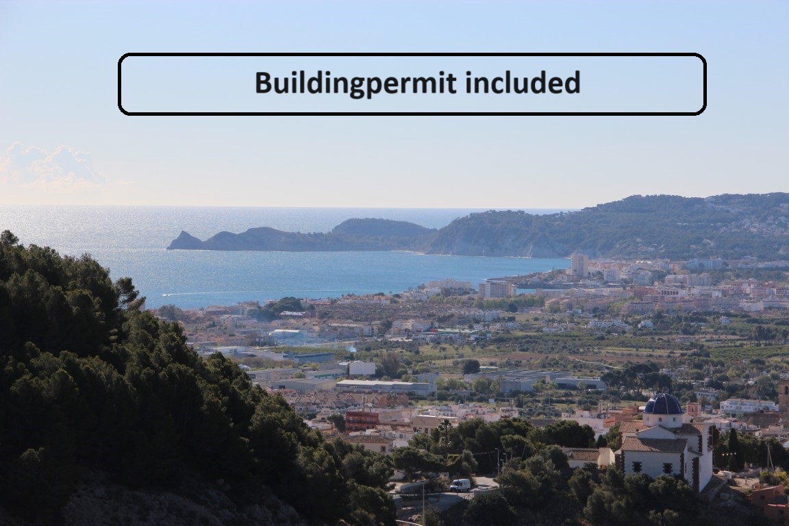 Panoramic views of the Jávea bay and Mediterranean Sea from the La Corona plot, featuring the town landscape and coastal headlands under clear skies.