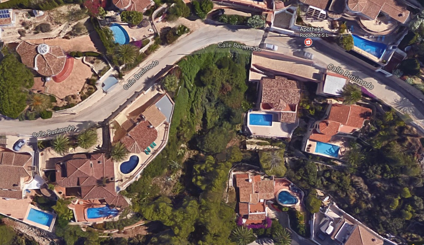 Aerial view of a plot in Benimeit, Moraira, surrounded by villas with pools and greenery.