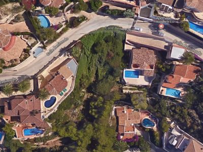 Aerial view of a plot in Benimeit, Moraira, surrounded by villas with pools and greenery.