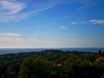 Panoramic view of Benimeit, Moraira, featuring the Mediterranean Sea in the background and a blue, cloudy sky.
