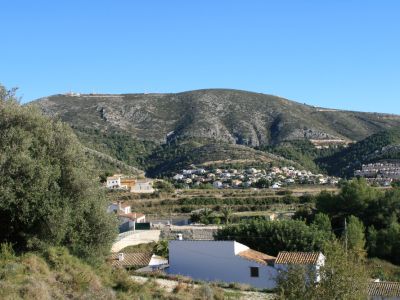 View of the Benitachell rural landscape with tiled-roof houses and a mountain backdrop.
