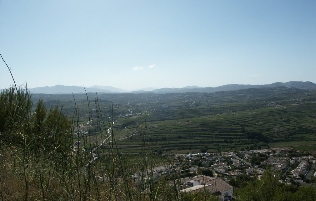 Panoramic view of Benitachell featuring agricultural terraces and distant mountains.