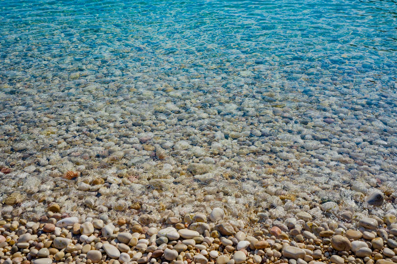 Detailed view of the crystal-clear turquoise waters and smooth white pebbles at Granadella beach, located in the natural surroundings near the villa in Jávea.