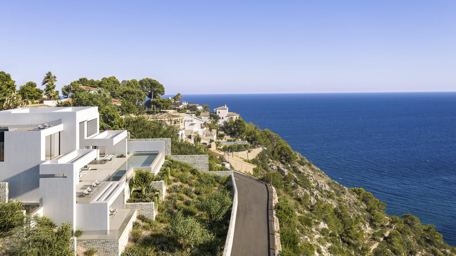Exterior view of the modern white villa featuring tiered terraces, an infinity pool, and panoramic Mediterranean Sea views from its cliffside location.