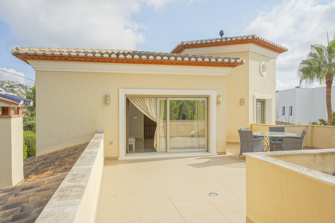 Spacious upper-level terrace featuring ceramic tiling, an outdoor dining set, and large sliding glass doors connecting to the master suite.