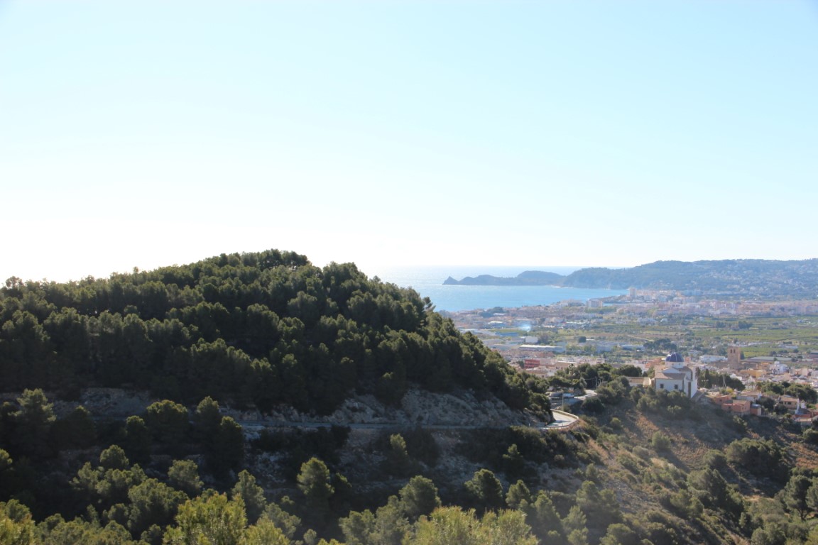 Elevated panoramic views overlooking the Javea valley, the Mediterranean coastline, and the historic town center featuring a traditional blue-domed church.